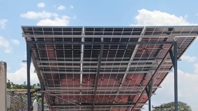 Paneles solares bifaciales sobre una estructura elevada de acero, vistos desde abajo contra el cielo